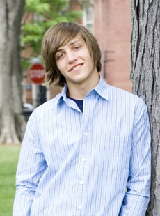 photo of boy leaning against tree